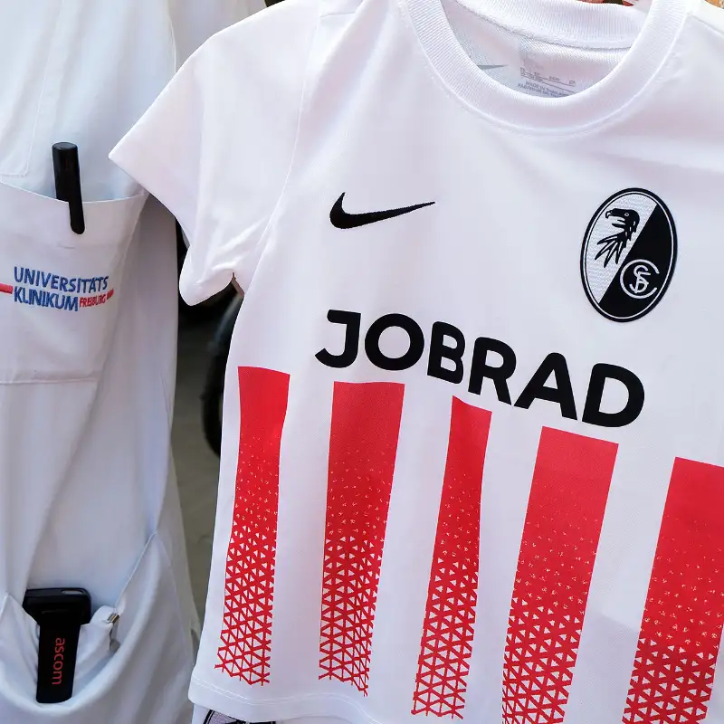 Eine Mitarbeiterin der Freiburger Geburtsstation hält das SC Freiburg Trikot mit JobRad Schriftzug hoch