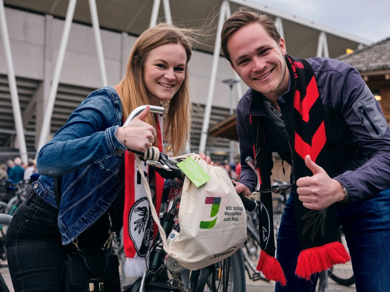 Ein Mann und eine Frau halten eine Goodie Bag am JobRad Aktionsspieltag Klimaschutz und machen beide die Daumen hoch Geste Ein Mann und eine Frau halten eine Goodie Bag am JobRad Aktionsspieltag Klimaschutz und machen beide die Daumen hoch Geste